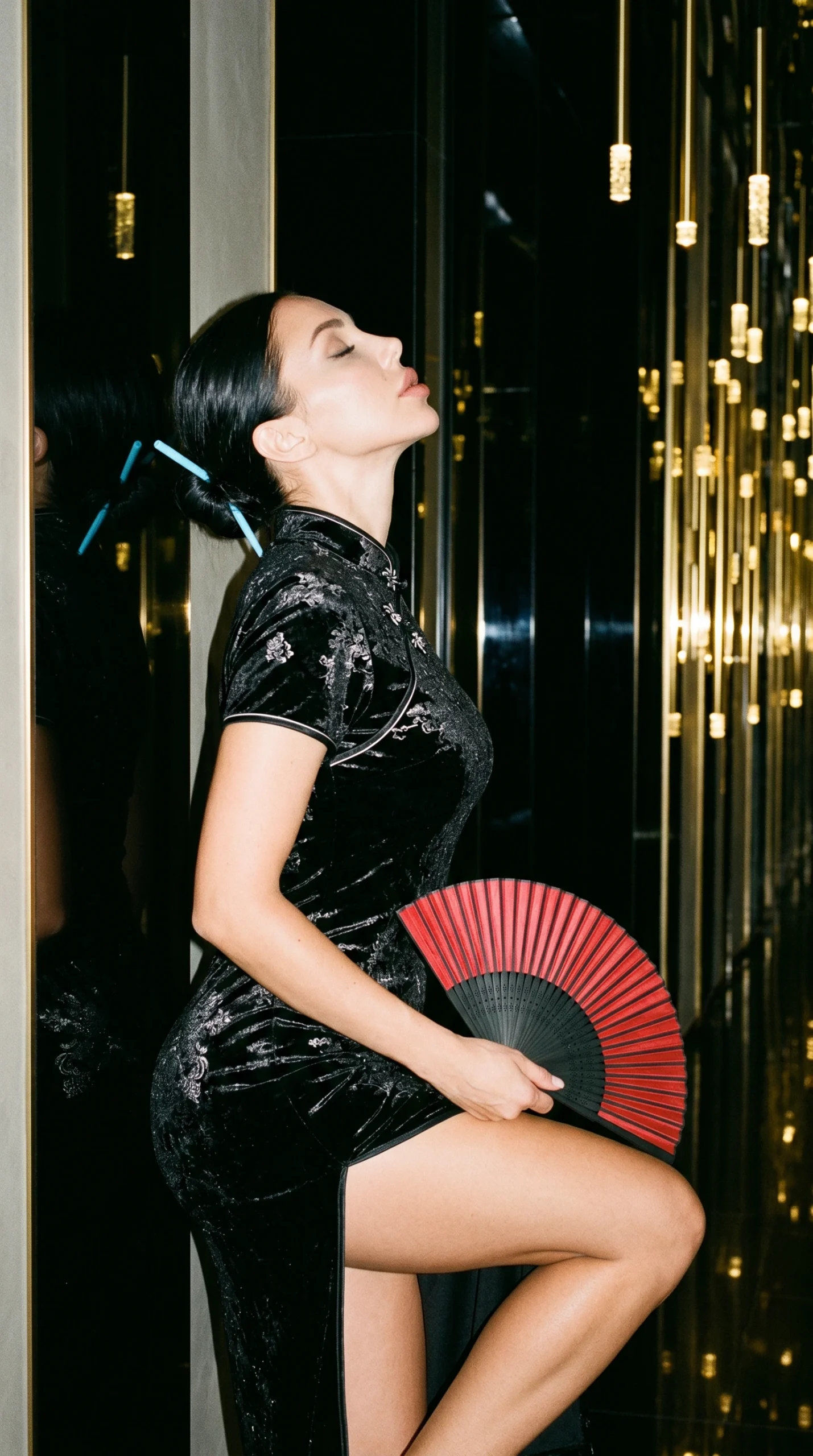 Woman in an Asian-inspired silk dress holding a decorative fan in a luxurious hallway with cinematic lighting
